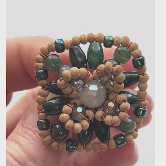 A square shaped ring with green gemstone beads interspersed between wood and crystal beads for full effect. Green jade with lighter crystal beads and natural wood for subtle effect.