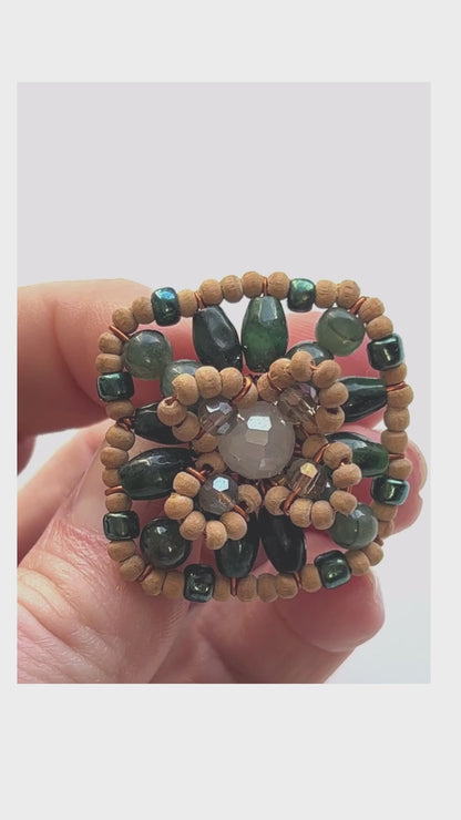 A square shaped ring with green gemstone beads interspersed between wood and crystal beads for full effect. Green jade with lighter crystal beads and natural wood for subtle effect.