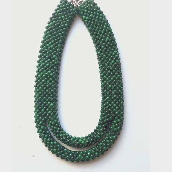 Made of malachite beads, the necklace is essentially a sleeve of malachite that splits into two at the bottom.
