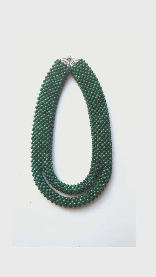 Made of malachite beads, the necklace is essentially a sleeve of malachite that splits into two at the bottom.