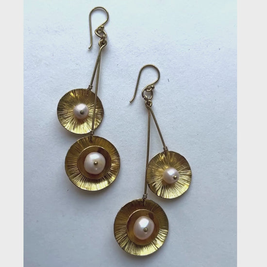 These dangling earrings have a unique design with a double drop with a round organic shape suspended at the bottom containing a pearl in the middle.
