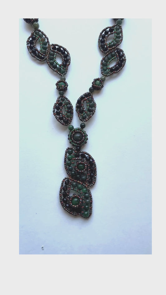 This pendant necklace features green gemstones woven into a stunning organic pattern - Sundara Joone.